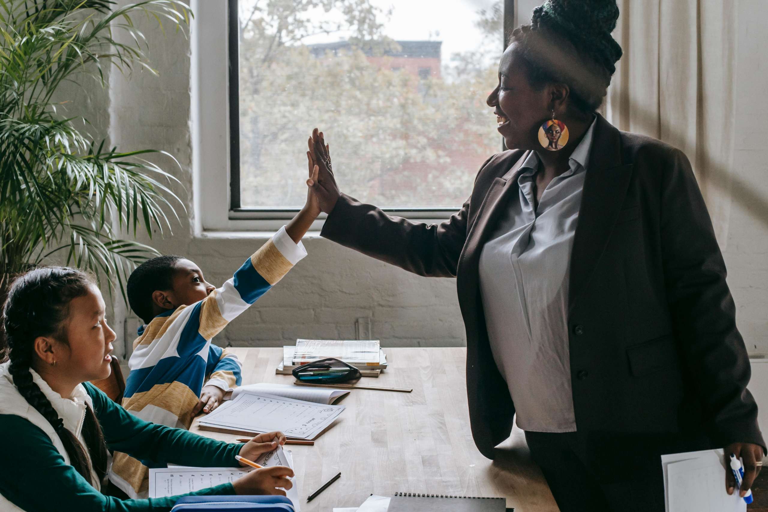 woman in blazer giving a high five to a student wearing a striped long sleeve tee.