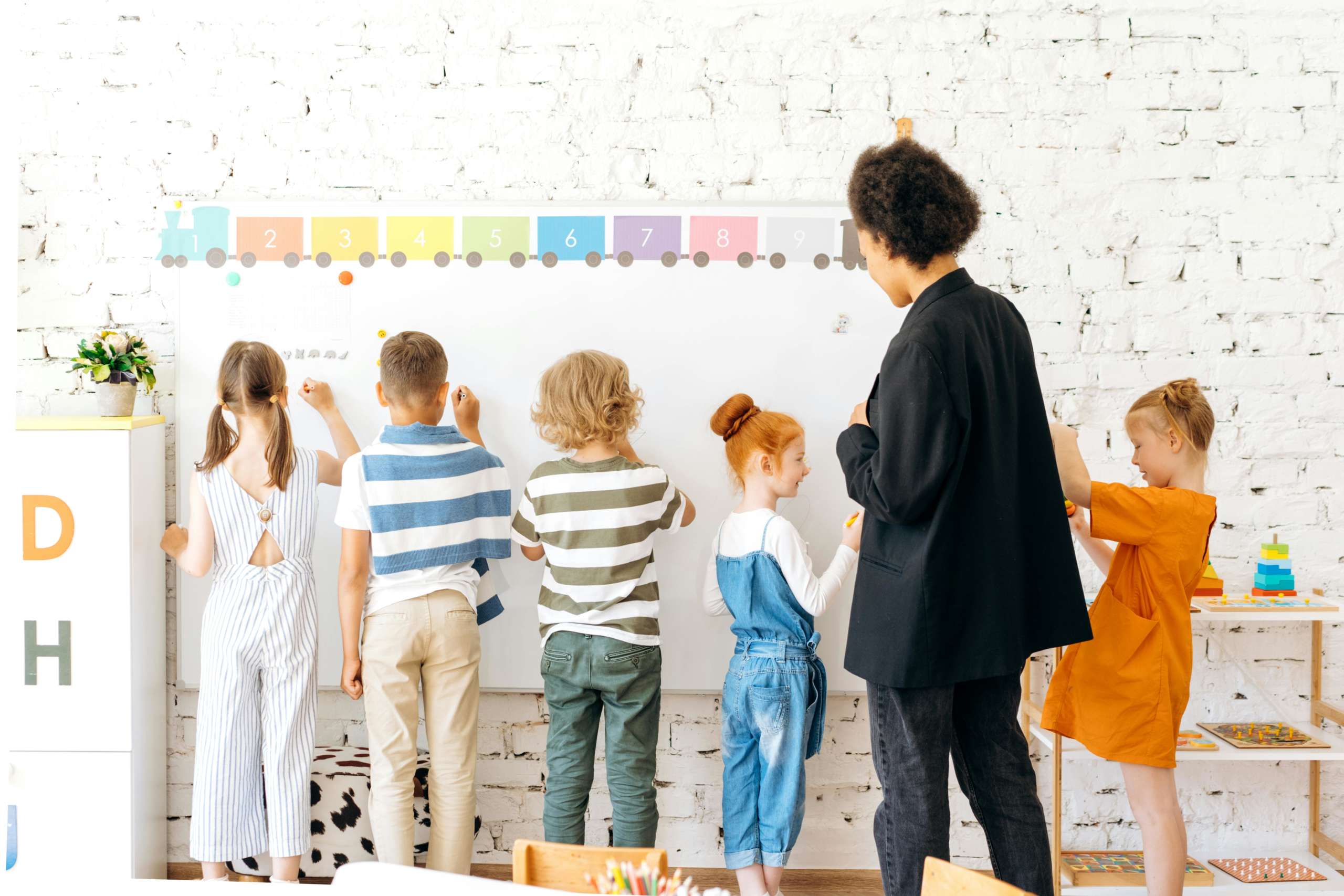 kids standing at a white board with their backs turned away from the camera