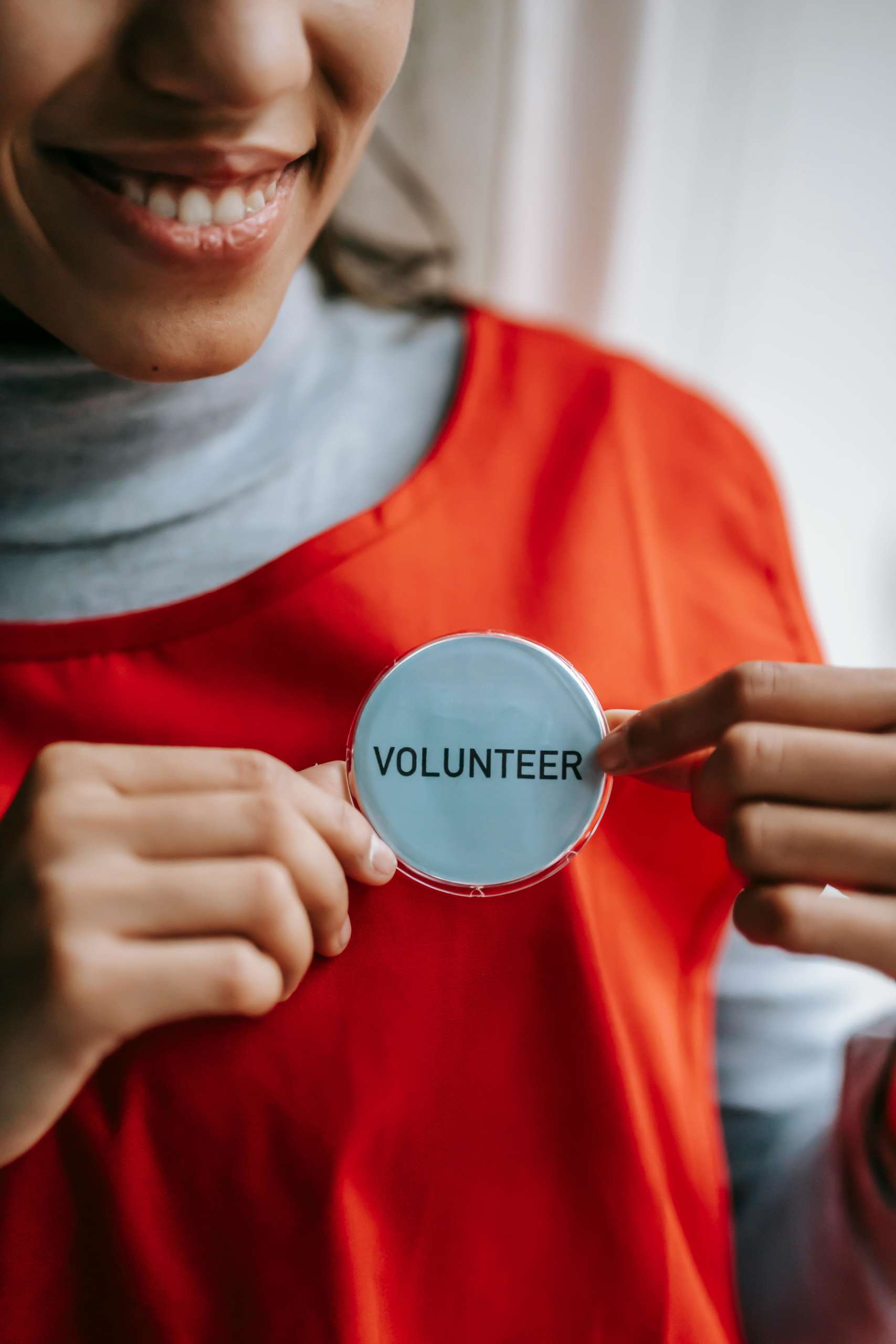 a woman in an orange tshirt holding a volunteer button